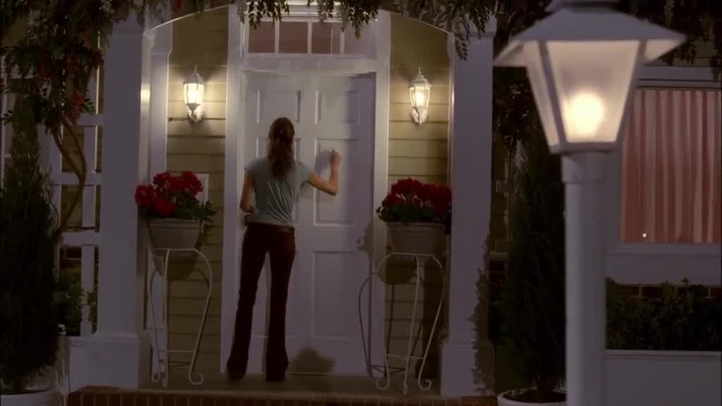 SUSAN holds a measuring cup and walks up to EDIE's front porch.jpg