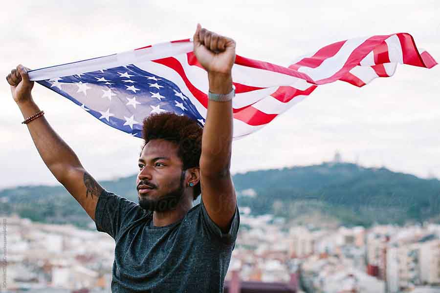 A young man holds a USA flag flying on top.jpg